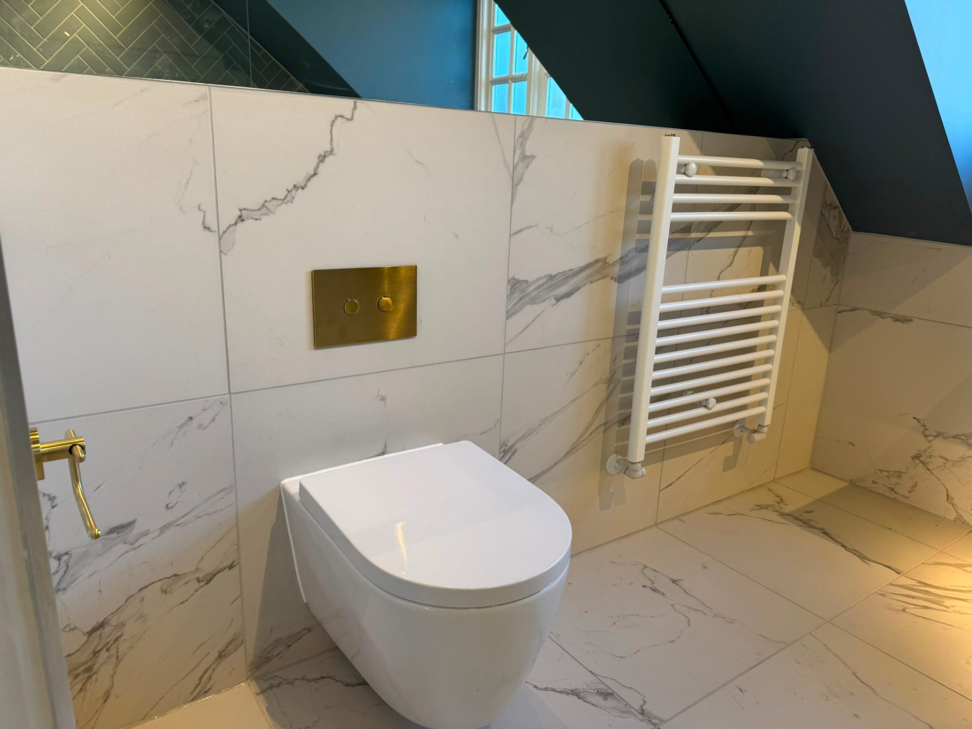Marble bathroom installation with wall-hung WC and chrome towel radiator in Ashford