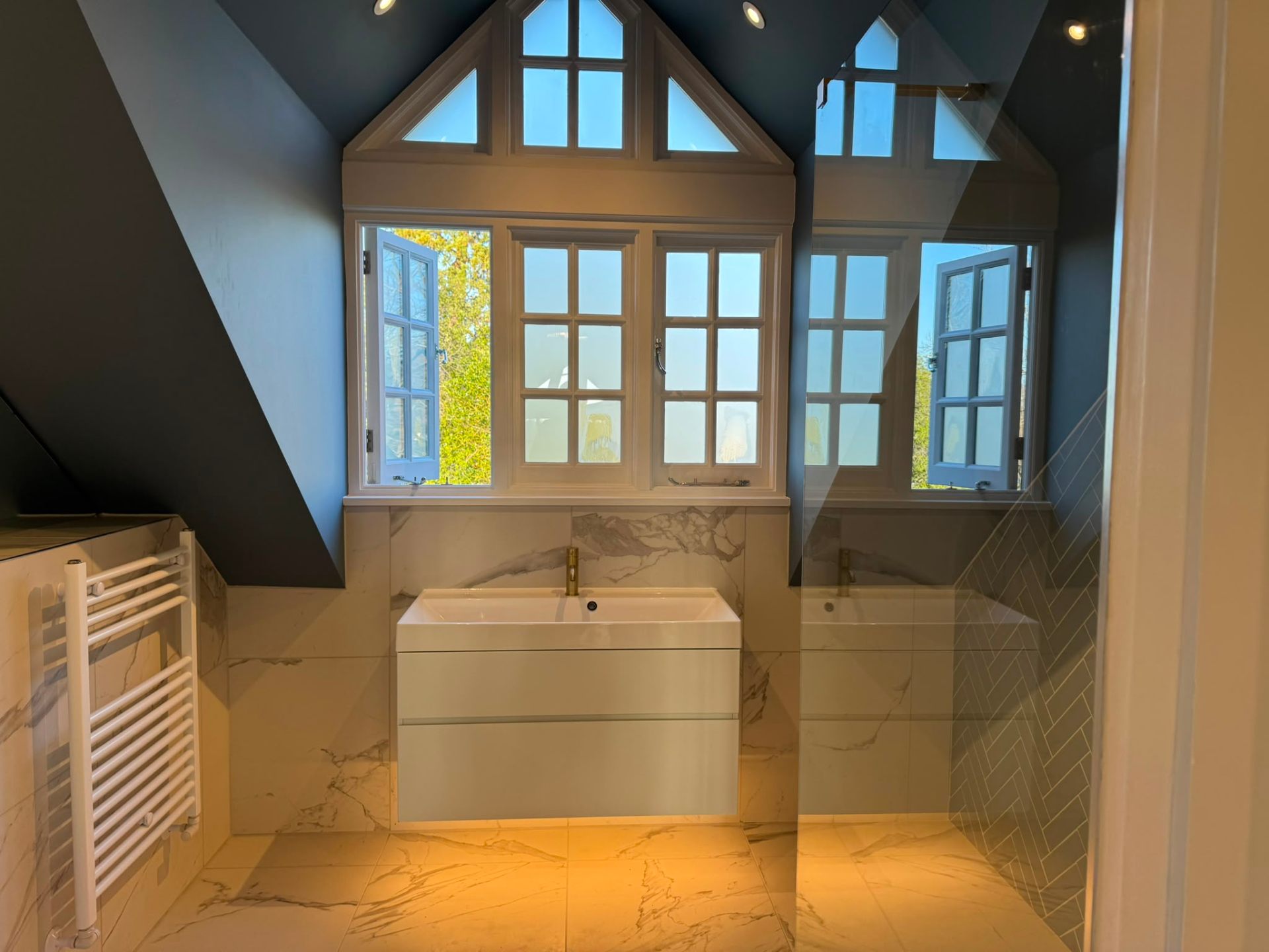 Loft bathroom installation with freestanding bath and marble tiling by Heat Solution London