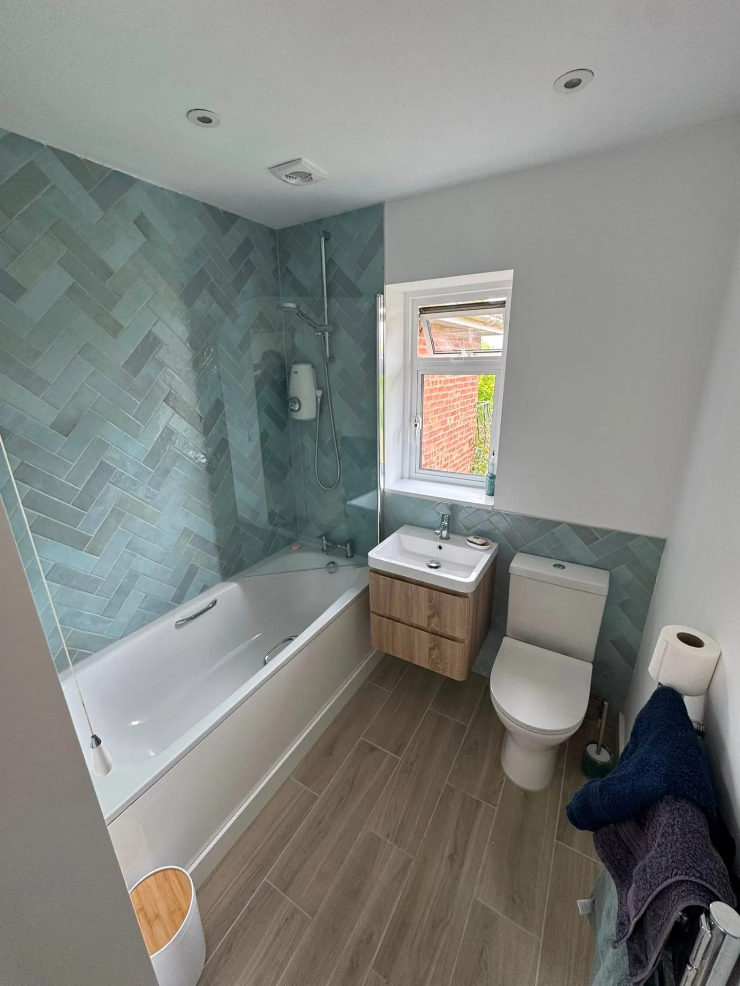 Herringbone-tiled bathroom installation with bath, WC and vanity unit in Surrey